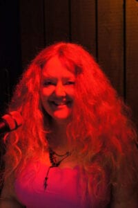 A woman with red hair and a microphone.